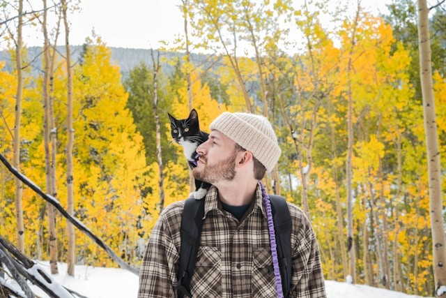 man-in-white-hat-and-plaid-shirt-with-black-and-white-cat-on-his-head